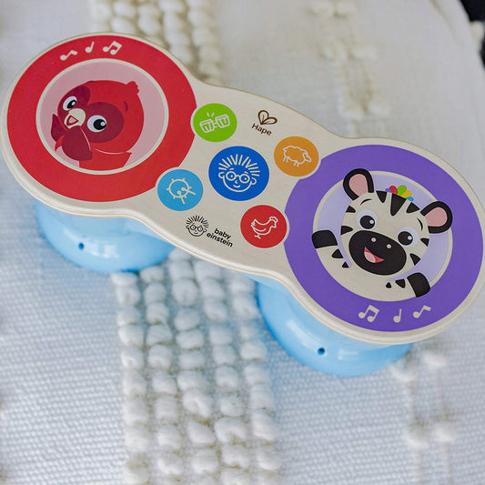 Drewniane bongo Hape Baby Einstein Magic Touch ustawione na tkaninie.