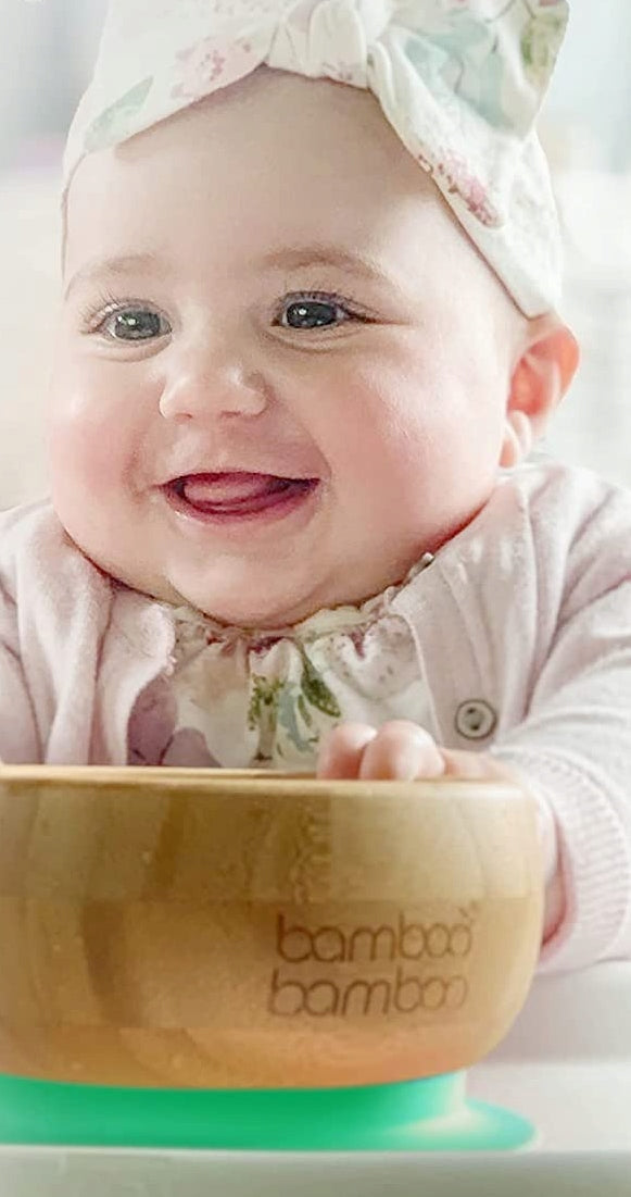 Poglądowe zdjęcie uśmiechniętego dziecka za miseczką z zieloną podstawą.