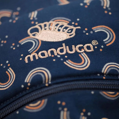 Zbliżenie haftowanego logo Manduca na tkaninie we wzór tęczy.